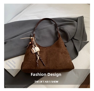 Détail du sac fourre-tout en daim marron avec un charme créatif en forme de tasse de café