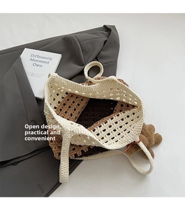 Detail of hollow woven tote bag with contrast trim and brown bear charm accessory