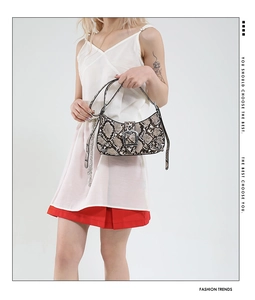 Detail of snake print underarm bag with metal buckle closure and adjustable strap
