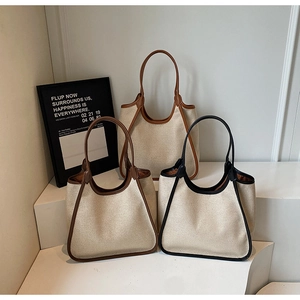 Trois sacs cabas en toile minimalistes avec finitions en cuir marron et noir sur support blanc
