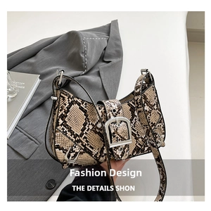 Detailed close-up of snake skin print handbag featuring a bold silver buckle ornament