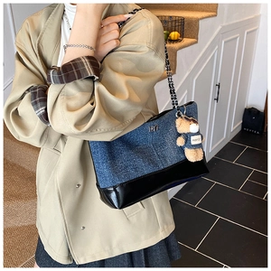 Detail of denim tote bag featuring black patent leather base and cute bear charm