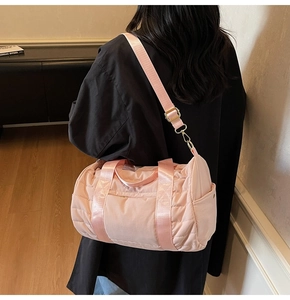 Detail shot of a pink quilted cylinder travel bag showing texture and adjustable strap