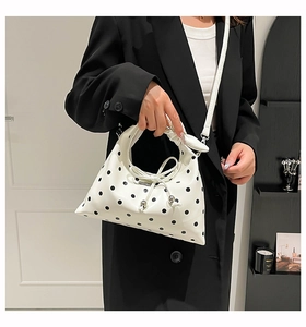 Detail of white polka dot handbag featuring a decorative drawstring and knotted bow handle