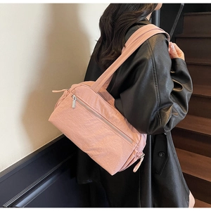 Pink nylon shoulder bag with zip pockets shown on female model in black leather jacket