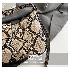 Close-up of brown snakeskin pattern shoulder bag with metallic buckle on gray fabric