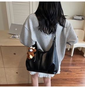 Vue détaillée d'un grand sac hobo en similicuir noir avec un joli pendentif d'ours brun