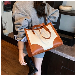 Détails des coutures contrastées en toile et cuir sur un grand sac cabas femme