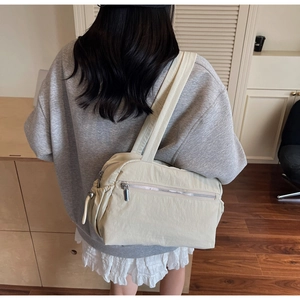 Detail view of large cream tote bag showing soft nylon texture and side zipper on model