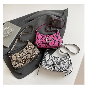 Detailed view of three snake-embossed faux leather baguette bags with silver buckle detail