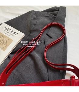 Close-up of a glossy red leather long shoulder strap with an adjustable smooth finish