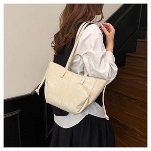 Detail of cream glossy leather tote bag showing smooth texture and side drawstring knots