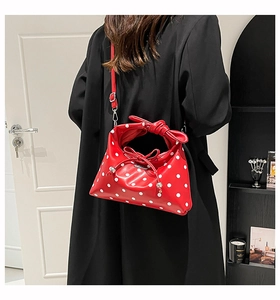 Detail of red polka dot handbag with large bow handle and detachable shoulder strap