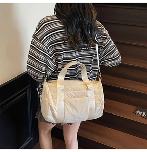 Detail view of cream quilted travel bag showing textured stitching and shoulder straps