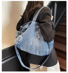 Detail of denim tote bag showing vertical zip pocket and round coin purse attachment