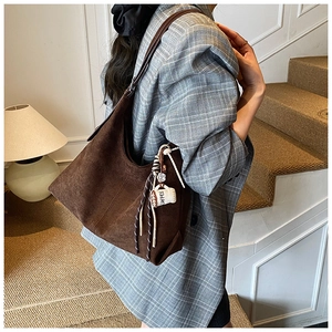 Détail du sac Hobo en daim marron foncé avec breloque tasse à café et accents de sangle
