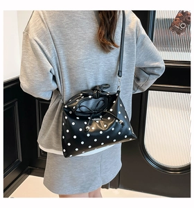 Polka dot handbag with knot handle and bow detail worn as a stylish crossbody bag