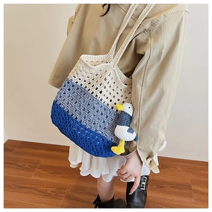 Detail of blue gradient woven tote bag with hollow mesh texture and seagull charm