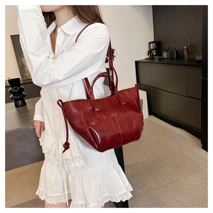 Detail of vintage red glossy faux leather tote bag with stylish side drawstring accents