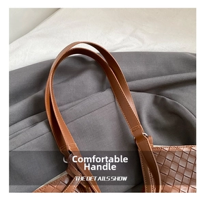 Close-up of brown woven tote bag showing smooth leather handles and detailed craftsmanship