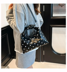Black tote bag with white polka dots featuring a decorative bow and detachable strap