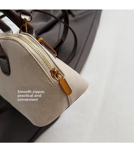 Detailed macro view of smooth metal zipper and brown leather trim on a retro shell bag