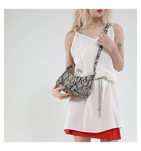 Close-up of retro snake skin pattern shoulder bag with silver buckle and rivets