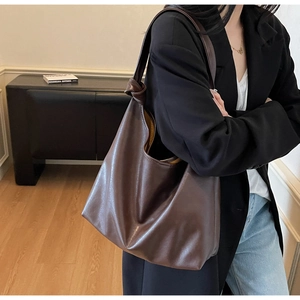 Detail view of dark brown leather tote bag showing the stylish knot design on the shoulder strap