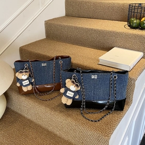 Retro denim patchwork tote bag with chain strap and teddy bear charm on carpet stairs