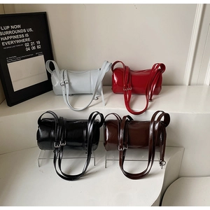 Showcase of four glossy patent leather cylinder bags in white, red, black and dark coffee