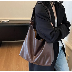 Detail of dark brown leather tote bag featuring a decorative knot on the shoulder strap