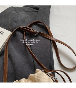 Detail of adjustable faux leather shoulder strap on a contrast woven bucket bag