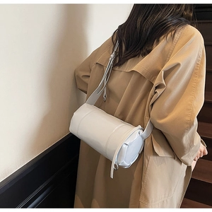 Detailed side view of light blue cylindrical crossbody bag with decorative strap