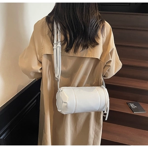 Detail of white cylinder shoulder bag featuring smooth leather and silver hardware