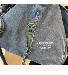 Detail of blue denim tote bag side zipper pocket holding a large smartphone