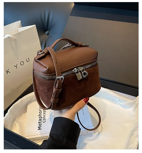 Detail of brown faux suede crossbody bag with top handle and textured leather patchwork