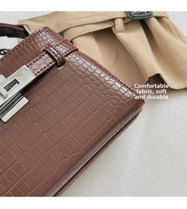 Detail of brown crocodile pattern leather texture and silver metal twist lock closure
