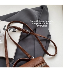 Detail of brown litchi pattern leather bag with adjustable strap and silver zipper