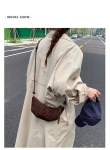 Détail d'un sac croissant en daim marron avec plis porté par un mannequin en manteau beige