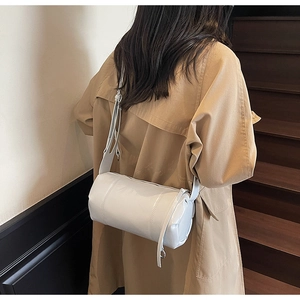 Detail view of the sleek white cylinder crossbody bag with adjustable leather strap
