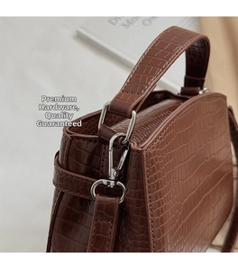 Close-up of crocodile embossed leather texture and silver metal hardware of Kelly bag