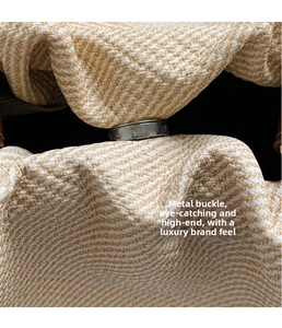 Detail of premium silver magnetic closure on a beige woven textured crossbody bucket bag