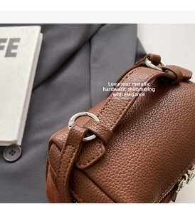 Close-up of deep brown leather bag showing litchi texture and silver metal hardware