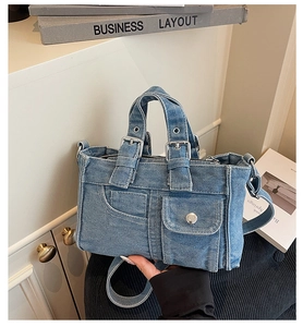 Macro detail of washed denim handbag with vintage buckles and metal button pockets
