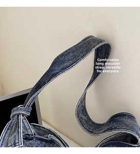 Macro shot of wide denim shoulder strap with reinforced stitching on retro blue tote