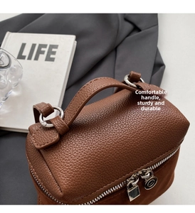 Close-up of brown litchi grain leather handle with silver metal zipper and lock detail