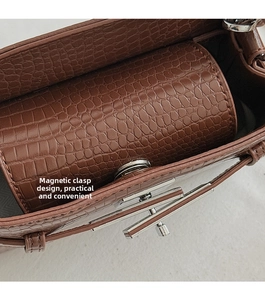 Detail of brown crocodile pattern handbag featuring a metal magnetic buckle closure