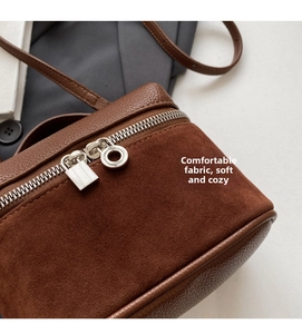 Detail of dark brown textured leather bag with suede splicing and silver zipper pull
