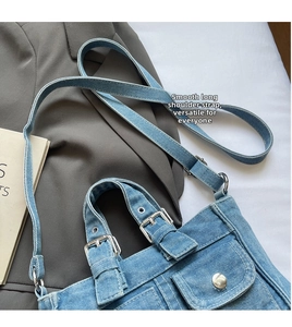 Detail of vintage denim crossbody bag featuring multi-pocket design and adjustable strap