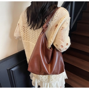 Back view of model wearing tan faux leather hobo bag with a stylish knotted shoulder strap